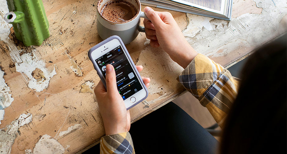 someone drinking coffee and using an iPhone