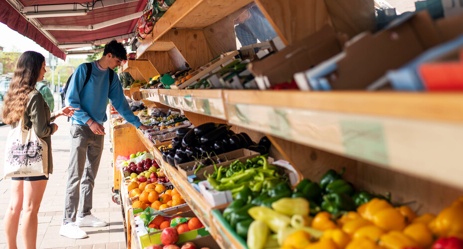 Two people choosing vegetables from a grocer's stand