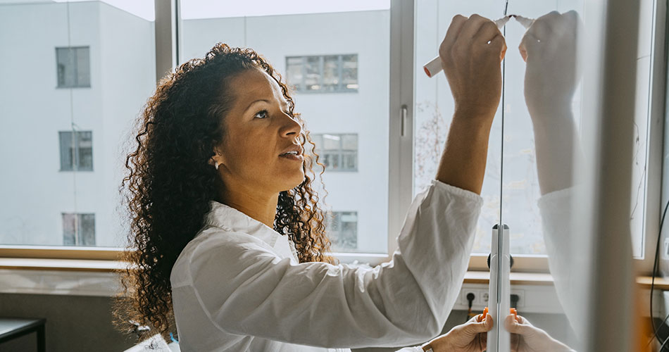A woman is writing on whiteboard within an institution